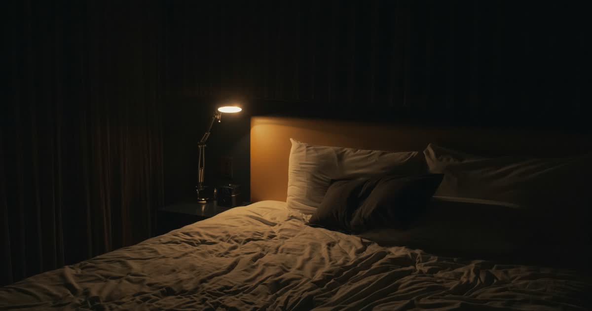 person lying in bed staring at ceiling wide awake in dark bedroom