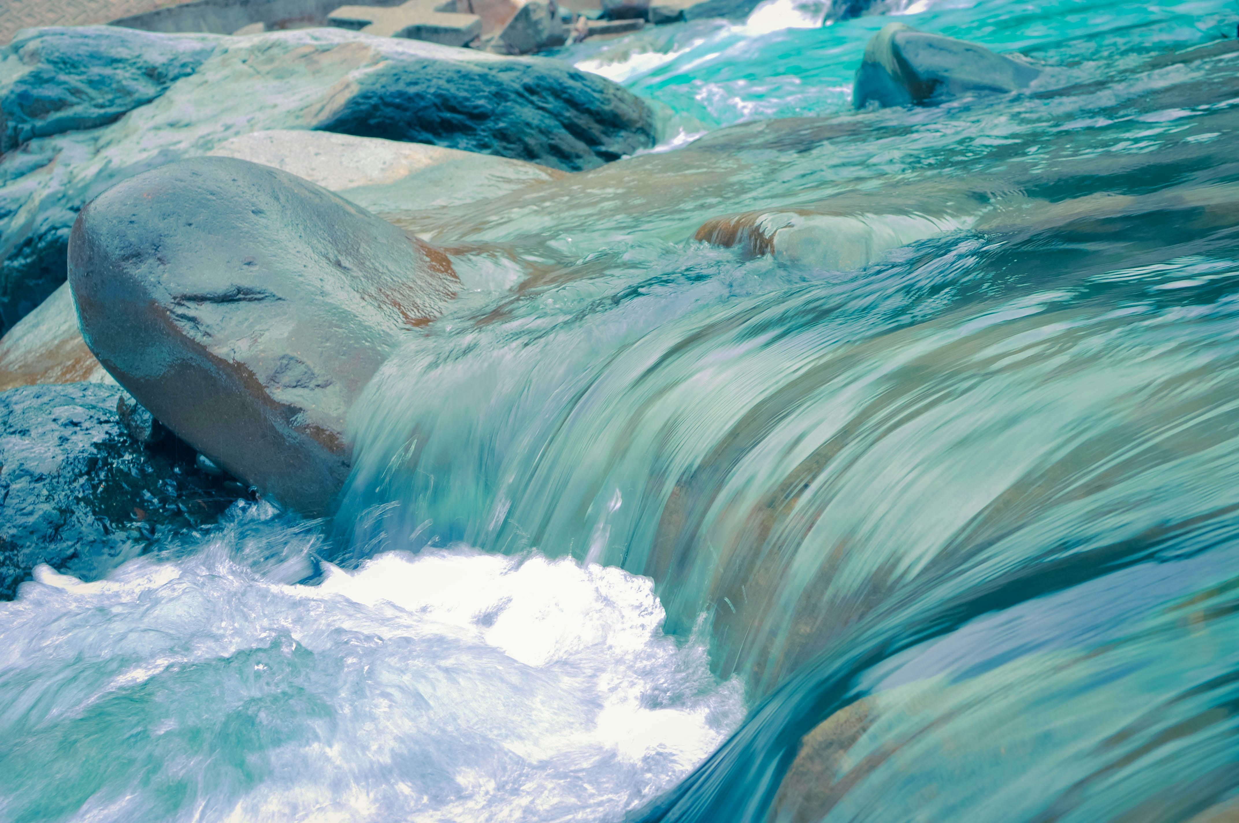 Clear turquoise water flowing smoothly over ancient stones — a visual metaphor for wu wei, effortless action in harmony with nature
